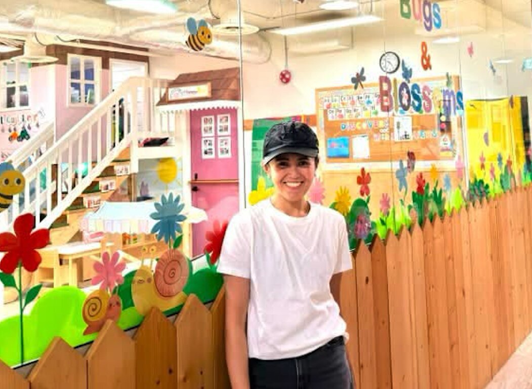 Jowena standing in front of a colorful classroom mural in a Canadian child care center