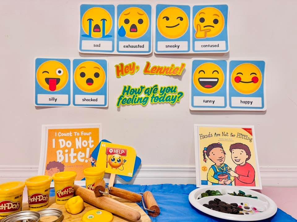 Emoji feeling cards on the wall above a clay activity table