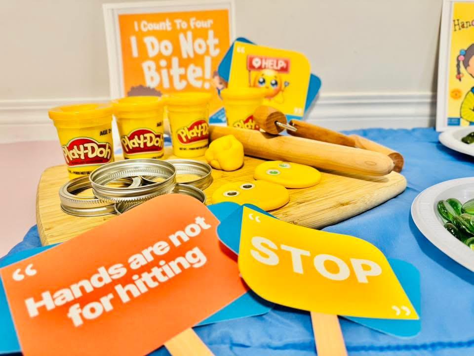 Close-up of clay faces, rolling pins, and 'hands are not for hitting' prompt cards